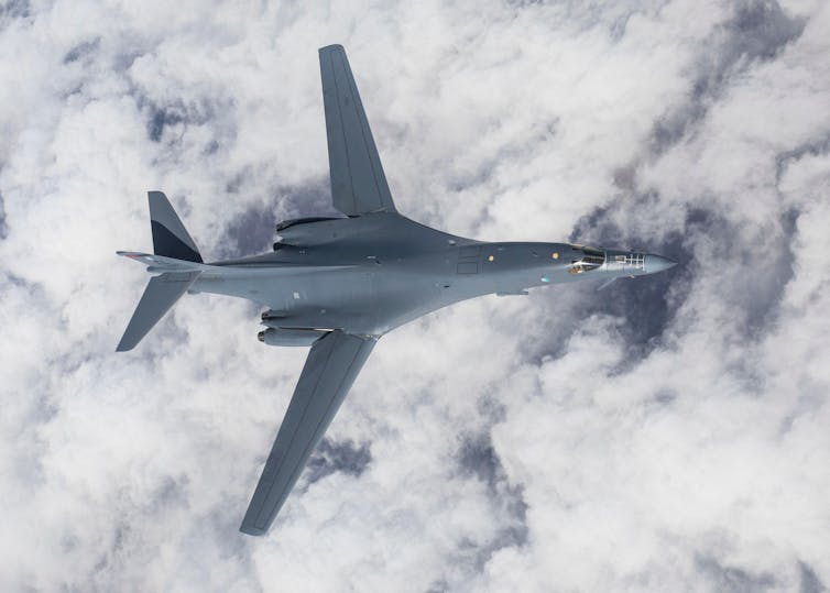 Military jet flying above clouds.