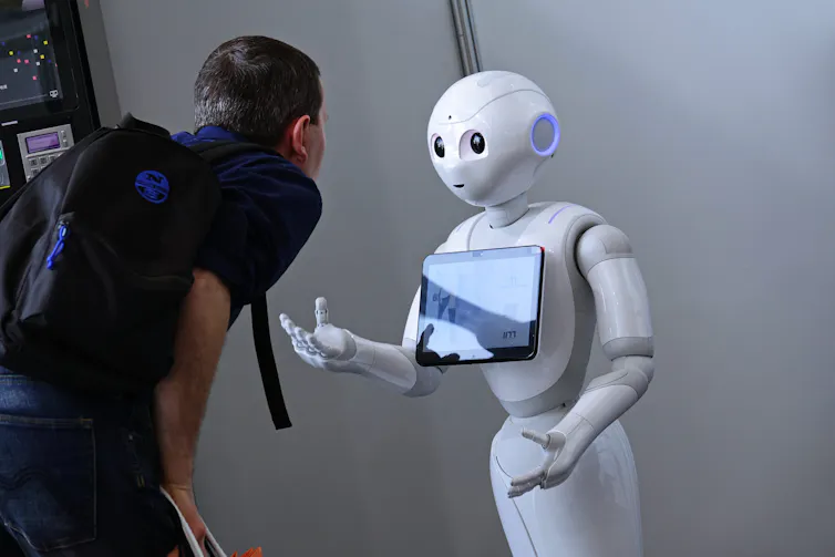 a man looks at a screen held by a robot