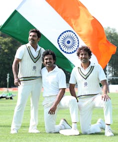 Three cricketers in front of the Indian flag.