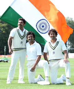 Three cricketers in front of the Indian flag.