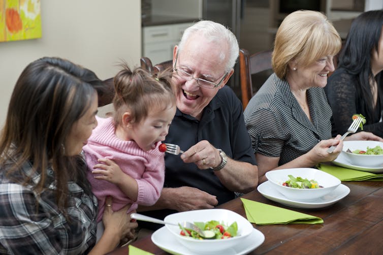 family table with older man feeding young child