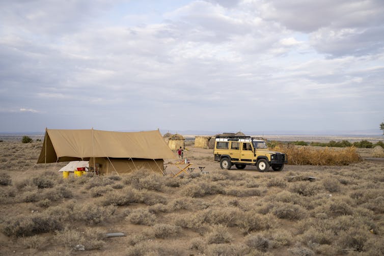 Tent and car in a grassland.
