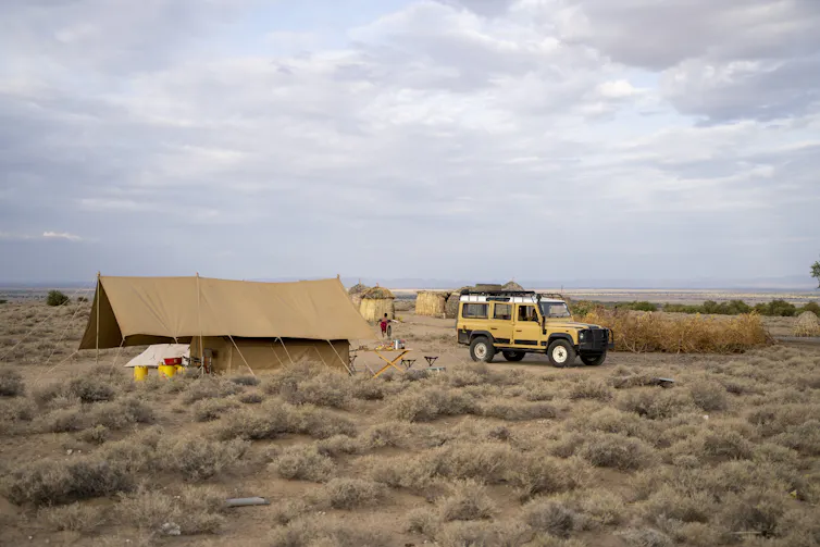 Tent and car in a grassland.