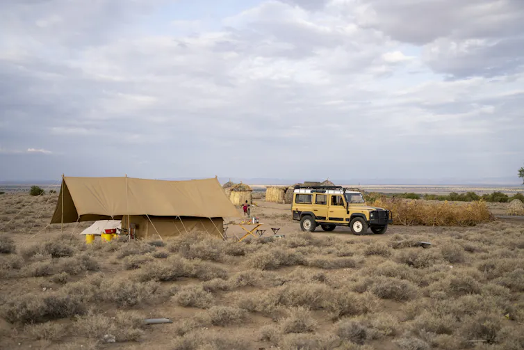 Tent and car in a grassland.