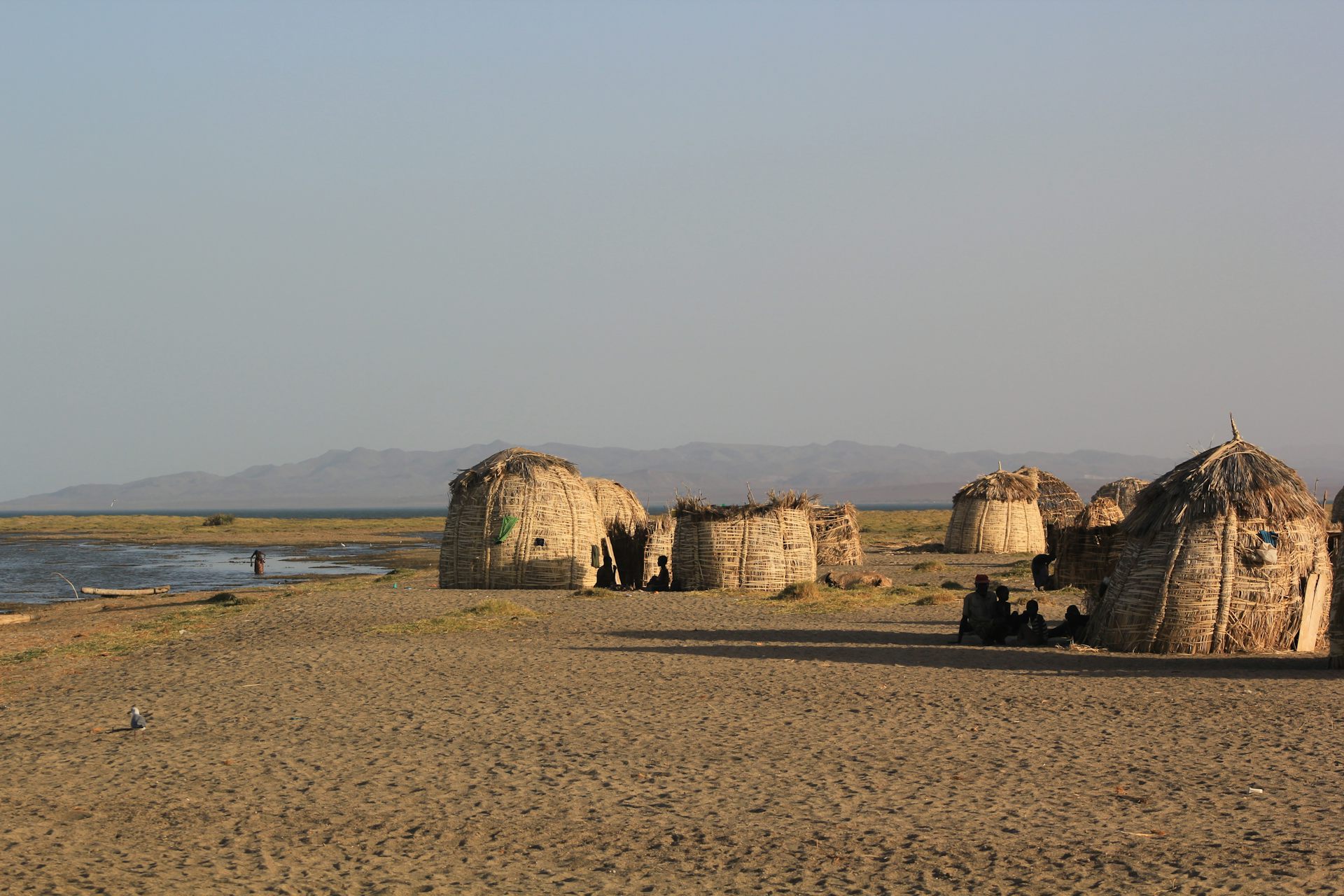 Traditional huts stand on the shore of a lake.