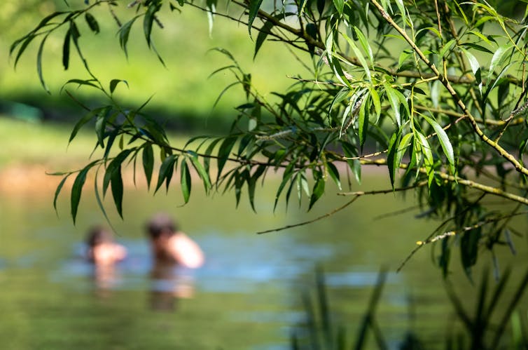 Two people bathe in a river out of focus.