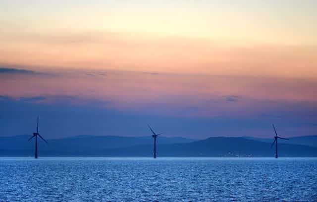 Offshore wind turbines with hills in background