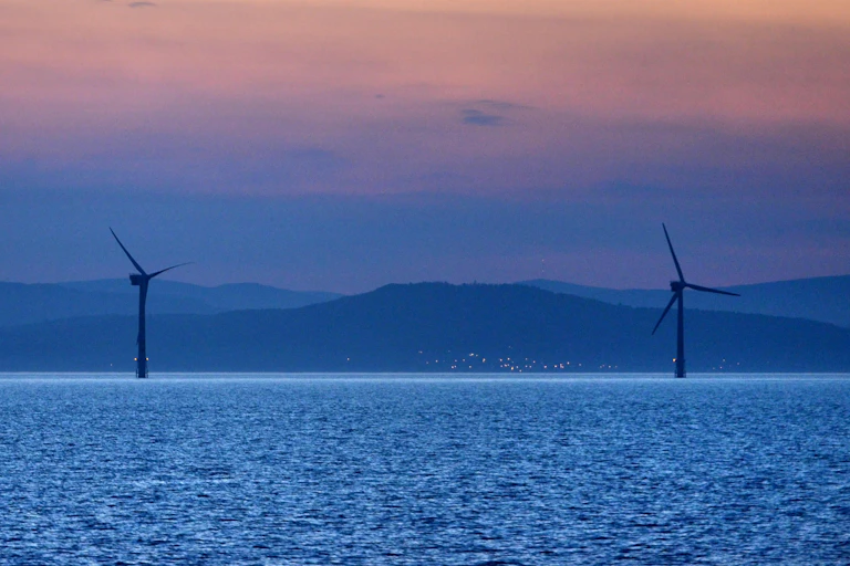 Offshore wind turbines with hills in background