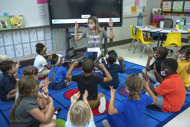 A teacher sits with a group of students.