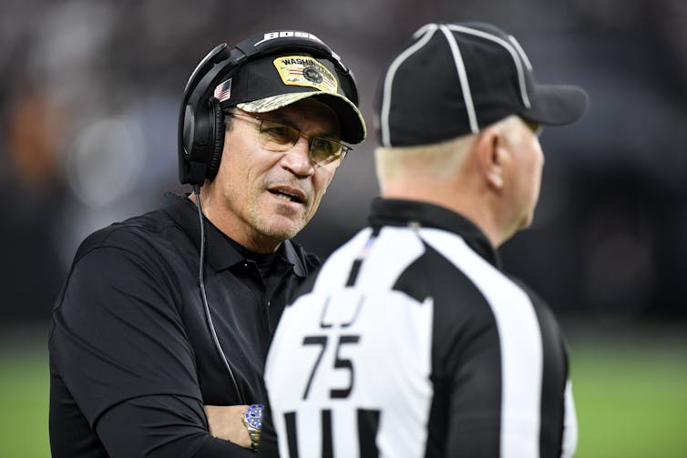 NFL coach Ron Rivera speaks to a referee.