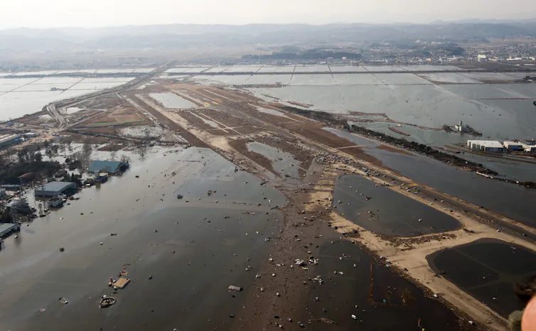 A flooded airport runway covered in debris.