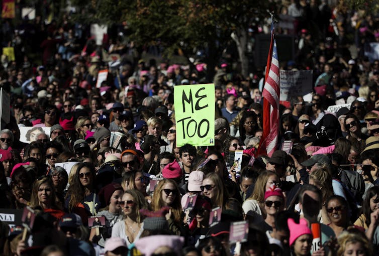 A bright green Me Too sign is seen amid a crowd of protesters.