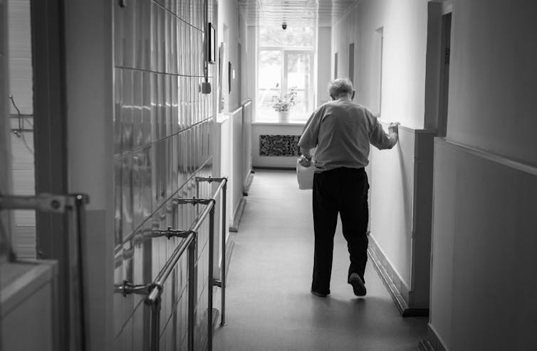Older man walks down corridor