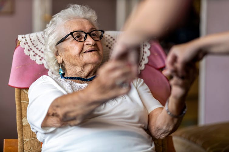 elderly woman holds hands of carer