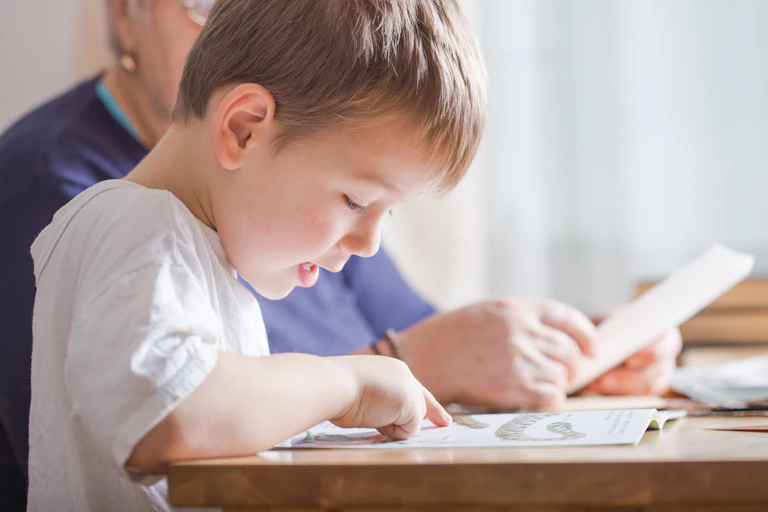 Young boy next to adult reading from book