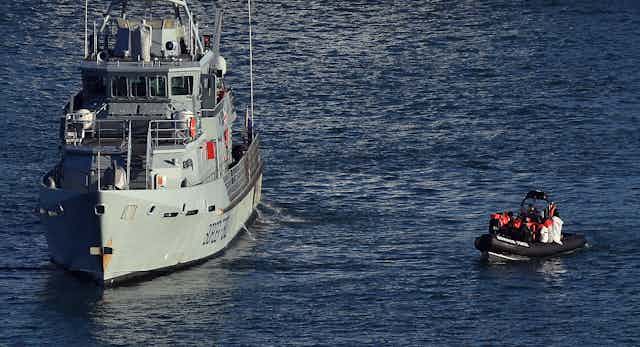 A Border Force vessel and a small lifeboat full of people surrounded by water