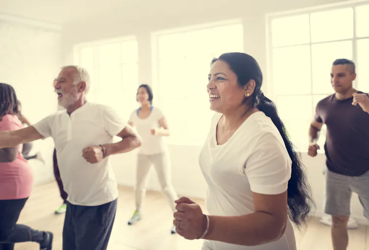 A group of people perform exercises in a group workout class.