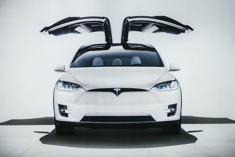 white Tesla model X on display with its doors open