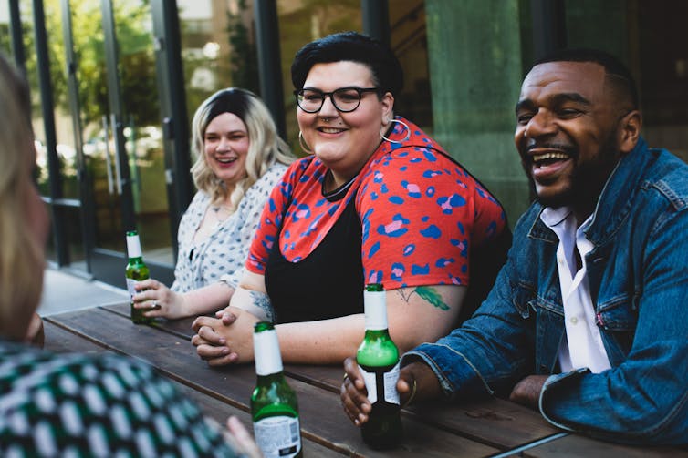 A group of friends laugh over beers in a pub.