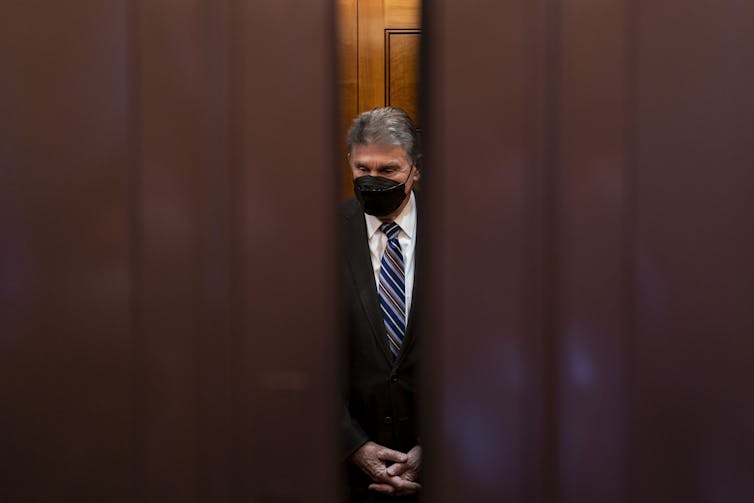 Sen. Joe Manchin of West Virginia stands behind closing doors.