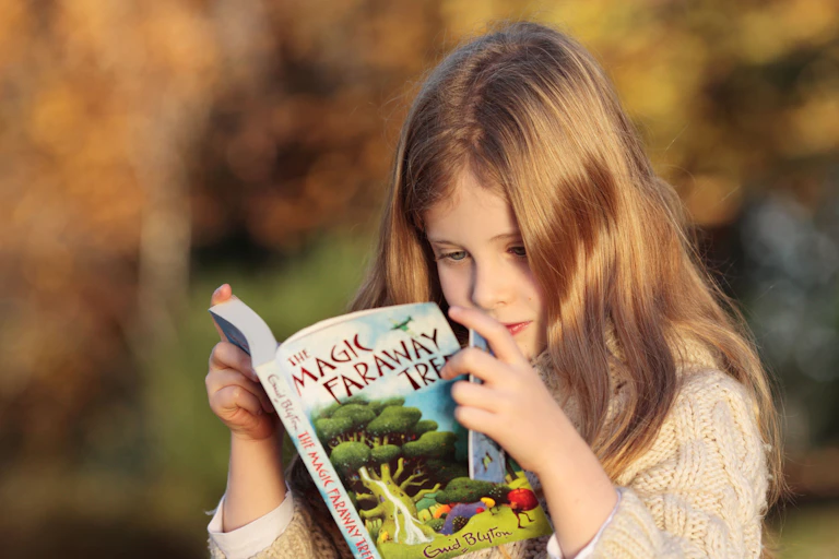 A girl reads a copy of The Magic Faraway Tree