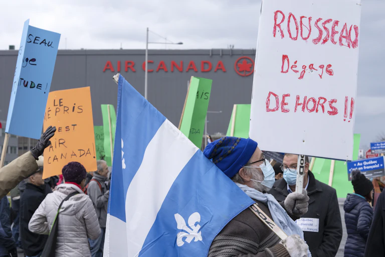 Un homme porte une fleur de lys et une pancarte condamnant le PDG d'Air Canada.