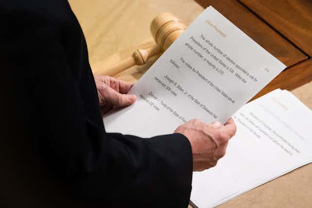 A sheet of paper with vote counts for president being held in Vice President Pence's hands.