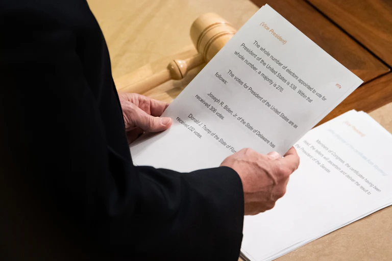 A sheet of paper with vote counts for president being held in Vice President Pence's hands.