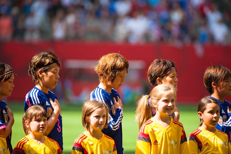 Japan players line up behind junior footballers ahead of a 2015 FIFA Women's World Cup match.