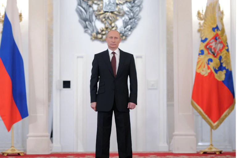 Vladimir Putin stands between two Russian flags