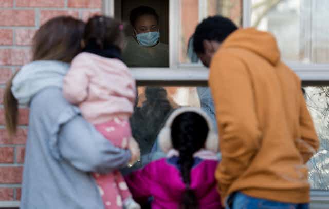 A family visits at a window of a long-term care facility