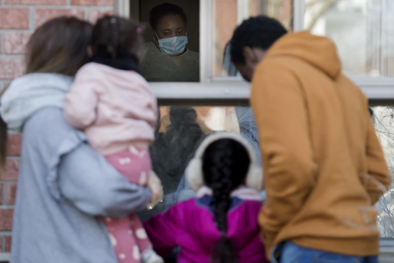 A family visits at a window of a long-term care facility