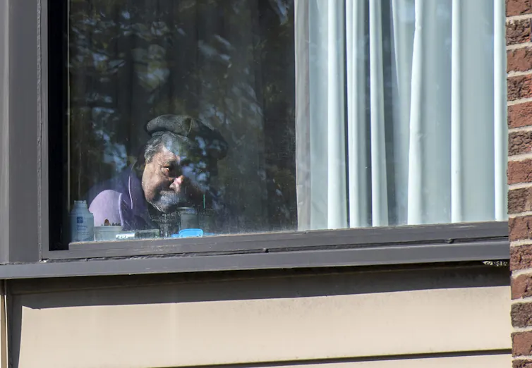 A person sits looking out their window