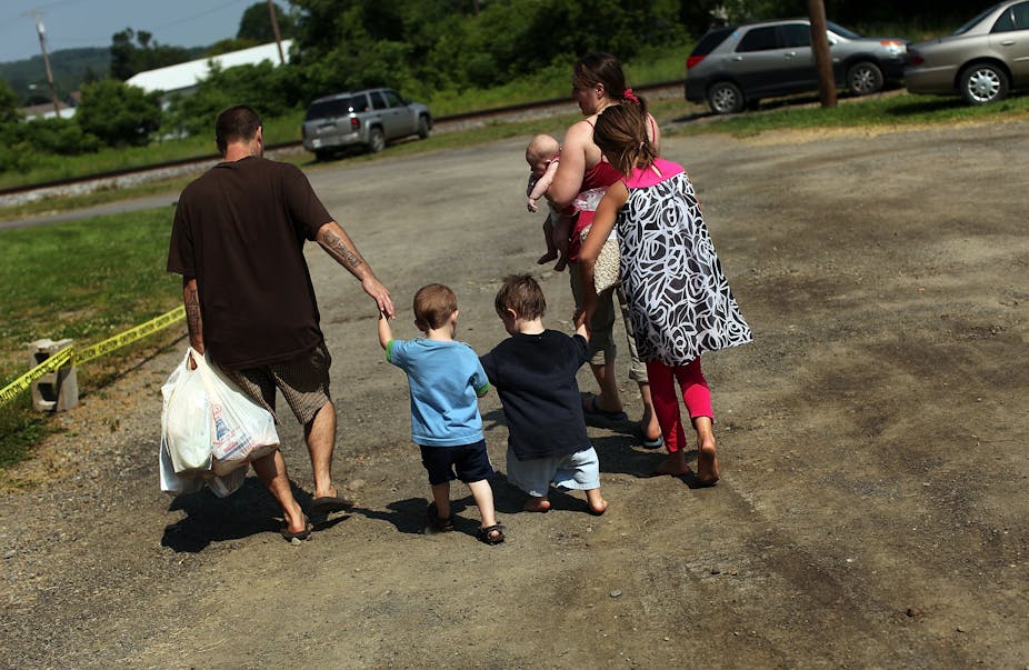 A family in upstate New York walks home carrying plastic bags filled with food after a food distribution from a food bank.