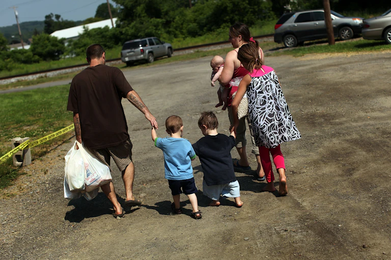 A family in upstate New York walks home carrying plastic bags filled with food after a food distribution from a food bank.