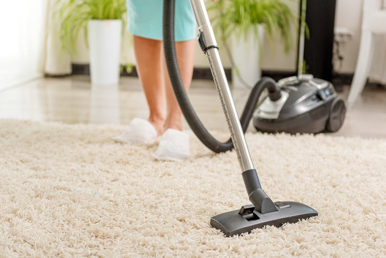 A woman vacuuming a rug