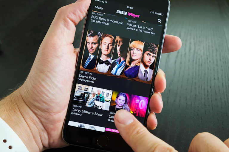 Person holding an iPhone with BBC iPlayer on it.