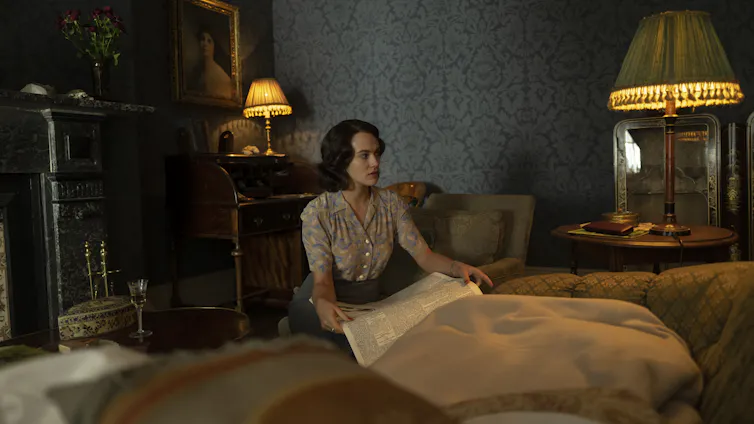 A woman kneels by a bed.