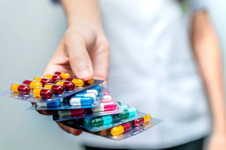 Woman holds five packs of antibiotics on her hand.