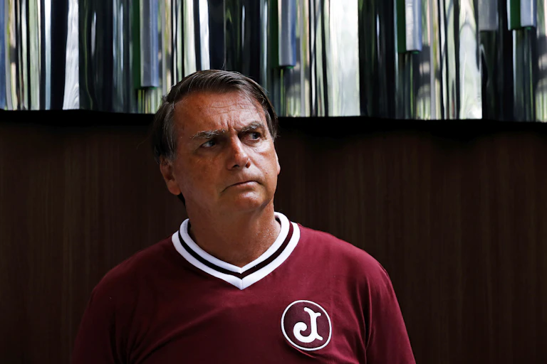 An older man with tanned skin and greying hair looks skeptically to the left. The photo is zoomed in, close-up on his face