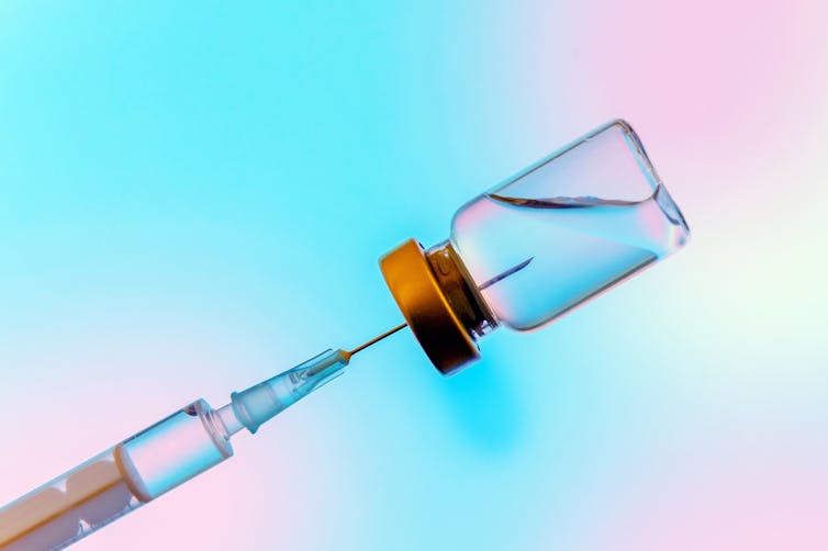 A syringe inserted into a vaccine vial.