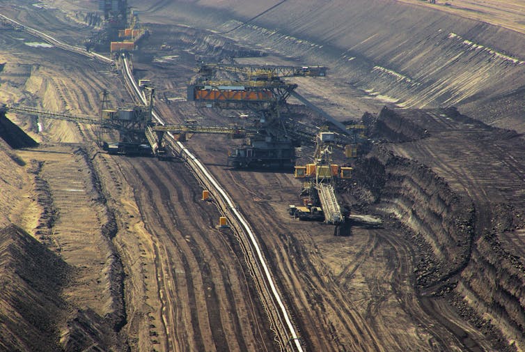 An aerial view of a coal mine with large excavators digging into the Earth.