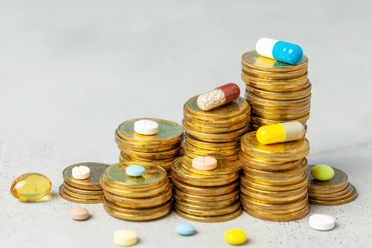 Stacks of coins with different coloured capsules and pills scattered around them.