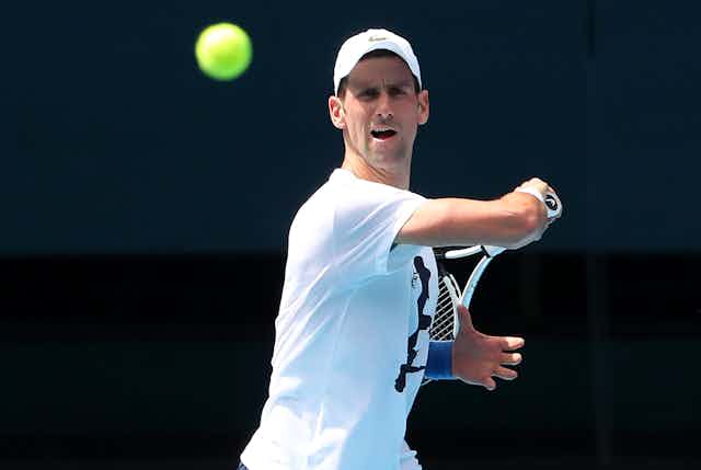 Novak Djokovic completes a swing during a practice session, the tennis ball is floating in front of him
