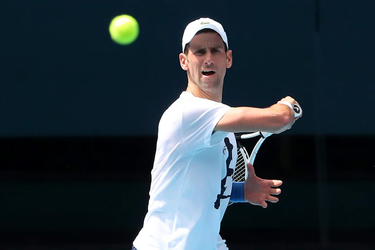 Novak Djokovic completes a swing during a practice session, the tennis ball is floating in front of him