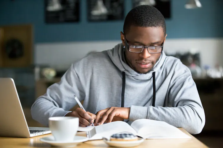 University student with glasses reads his book.