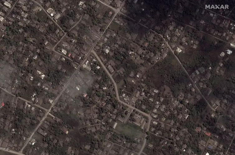 An aerial image of a residential area darkened by a coating of volcanic ash.