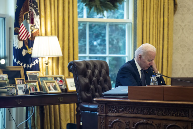 Joe Biden making phone call from his desk in the Oval Office.