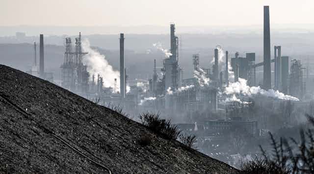 A coal mine dump in the foreground with an oil refinery behind it. 