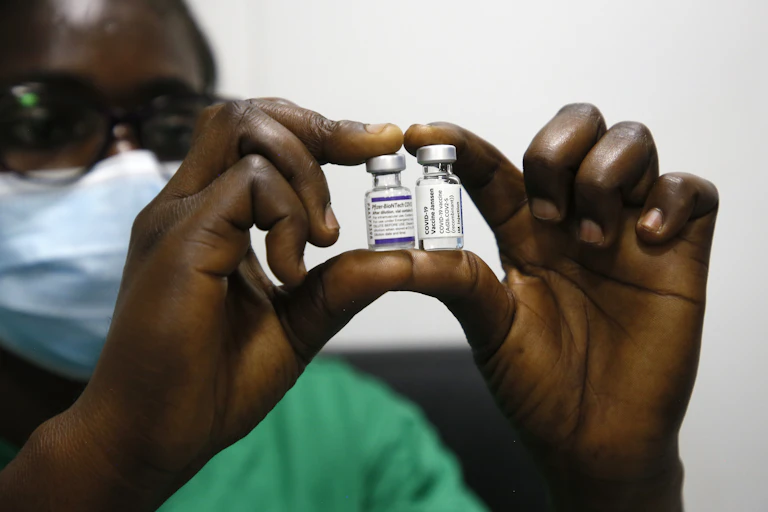 Medical worker holds up two phials of COVID vaccine